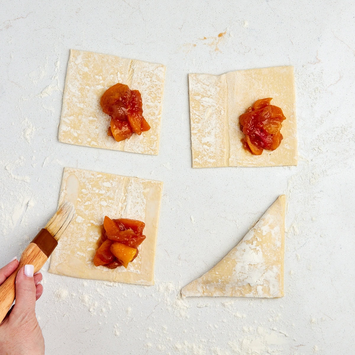 egg wash being brushed along edge of puff pastry.
