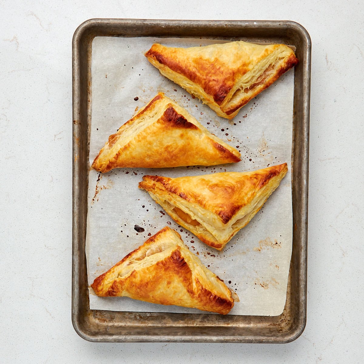 4 baked turnovers on a sheet pan lined with parchment paper.