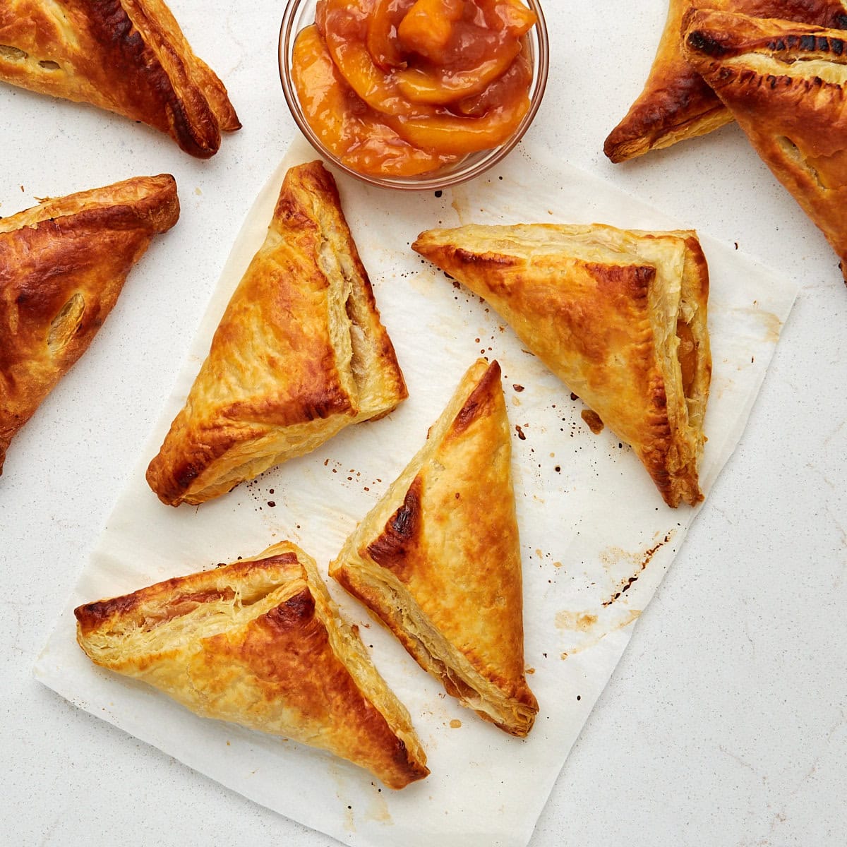 8 baked turnovers on parchment paper cooling.