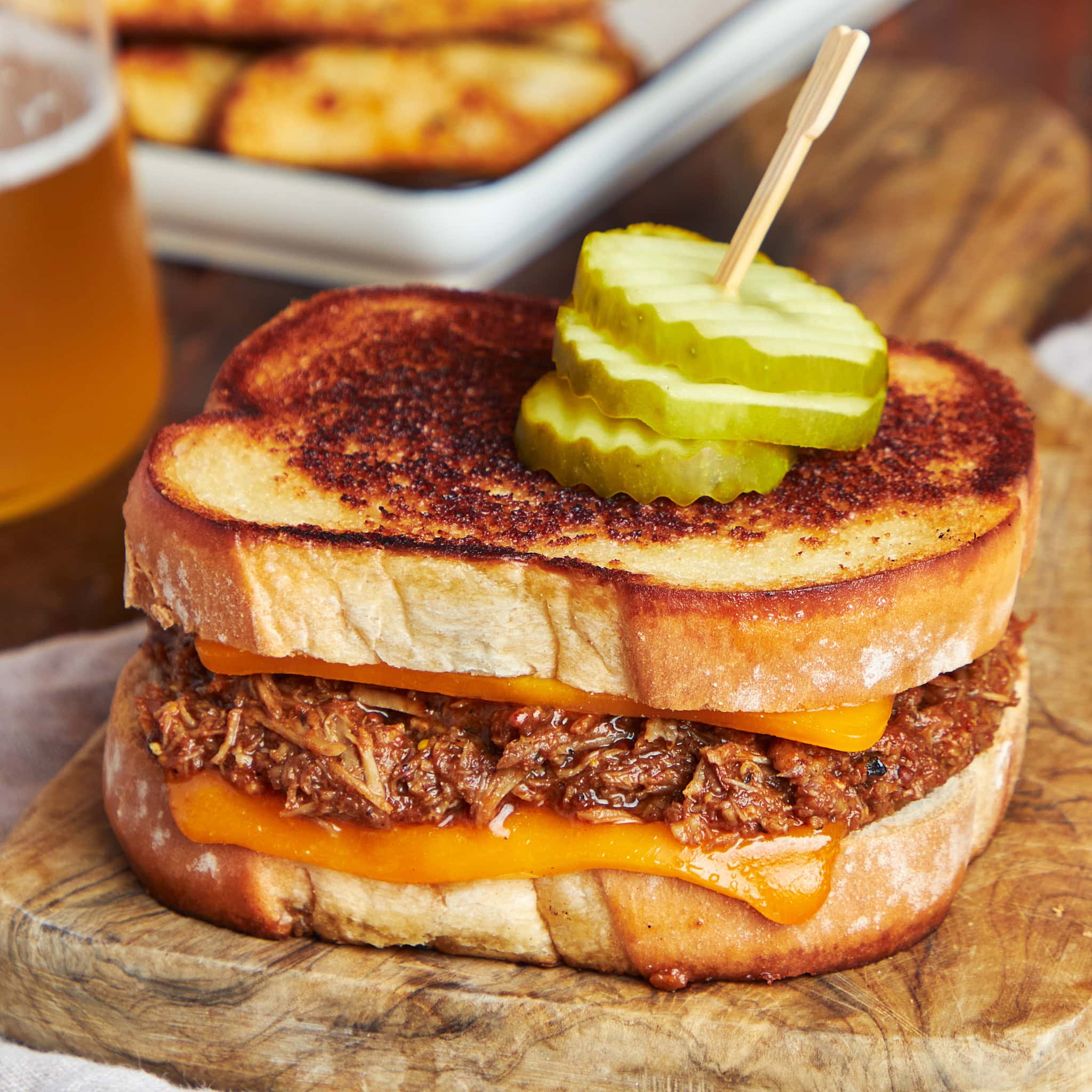 BBQ pulled pork grilled cheese served on a wooden board.