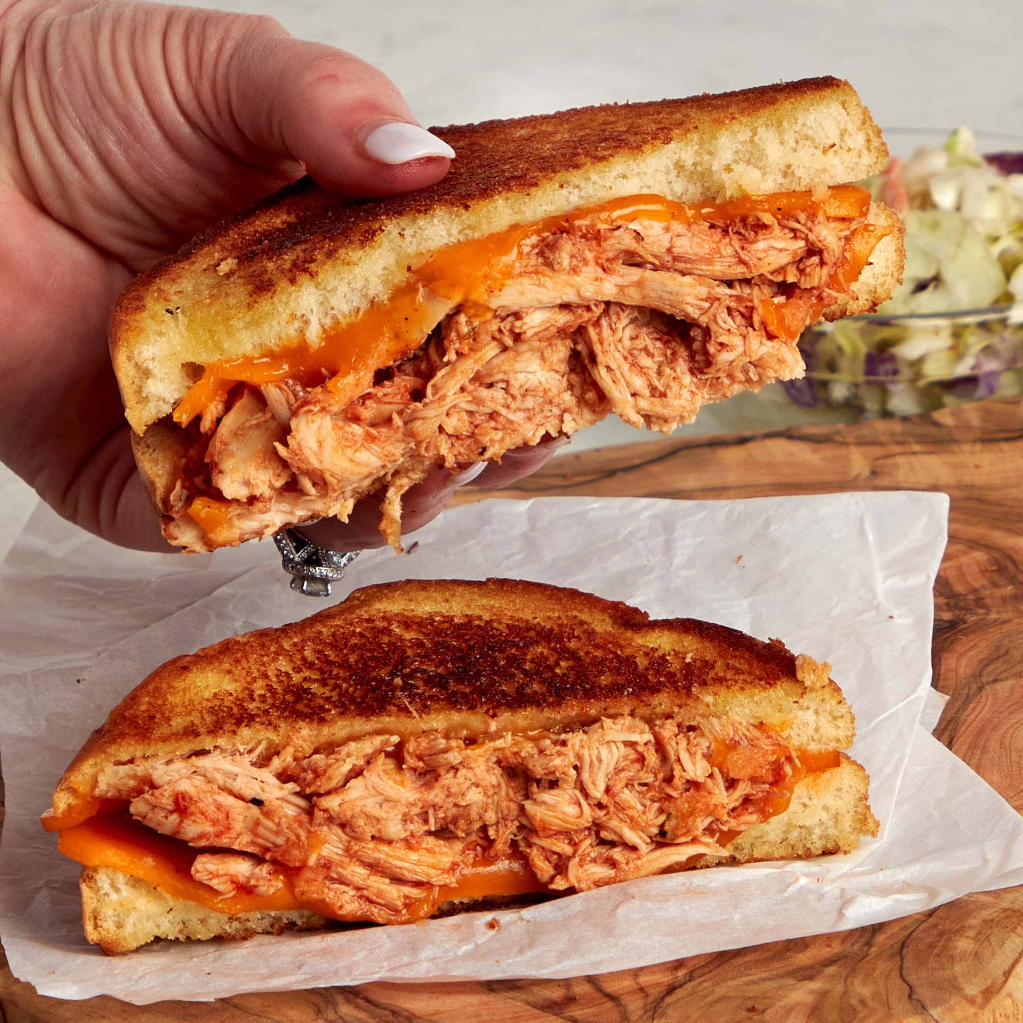 bbq chicken grilled cheese sliced on the diagonal with half on the plate and one half being held.
