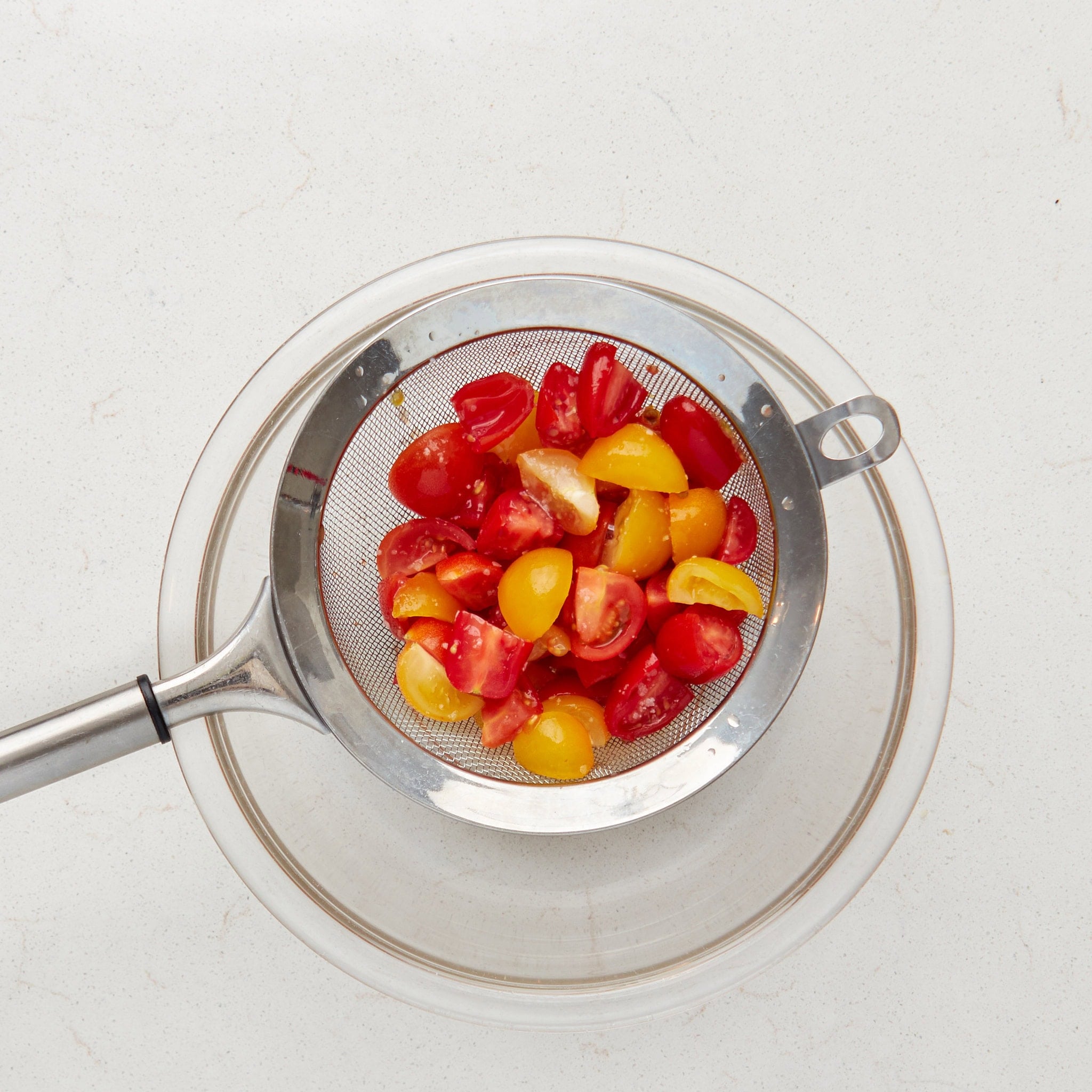 cut and salted tomatoes in a fine mesh strainer over a bowl.