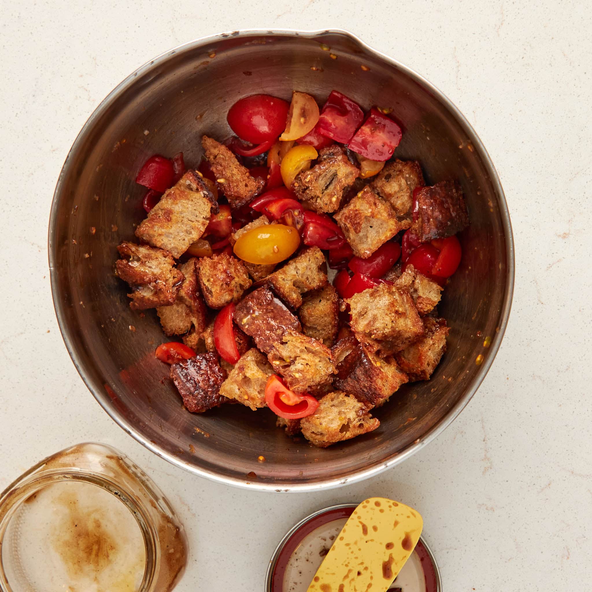 toasted bread and tomatoes in a bowl coated with dressing.