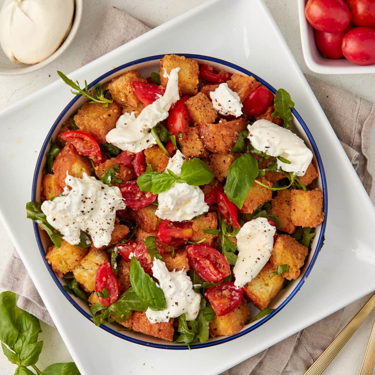 panzanella salad served on a white plate garnished with fresh basil.