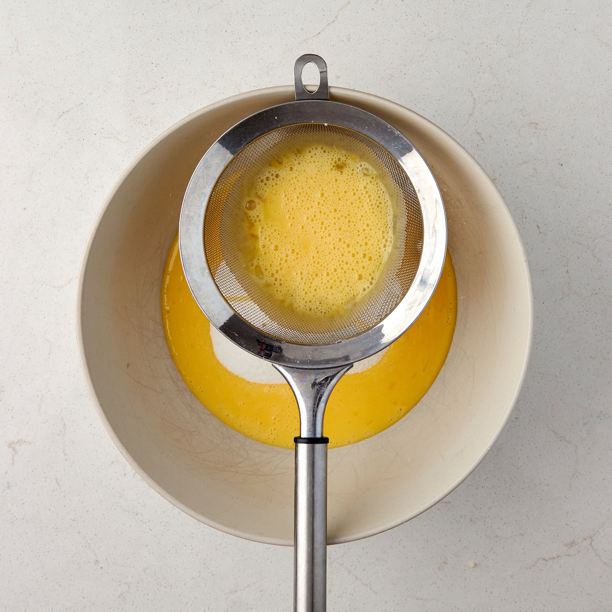 eggs being put through a fine mesh strainer.