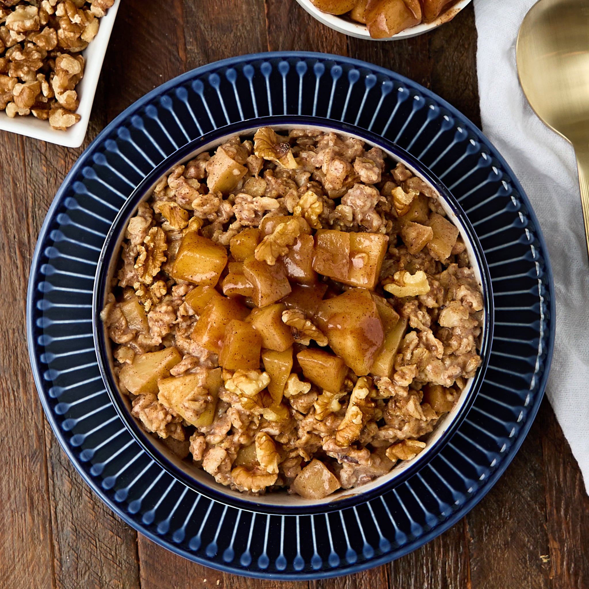 apple pie oatmeal served in a white bowl on a blue plate.