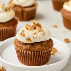 carrot cake muffin with cream cheese frosting topped with walnuts.
