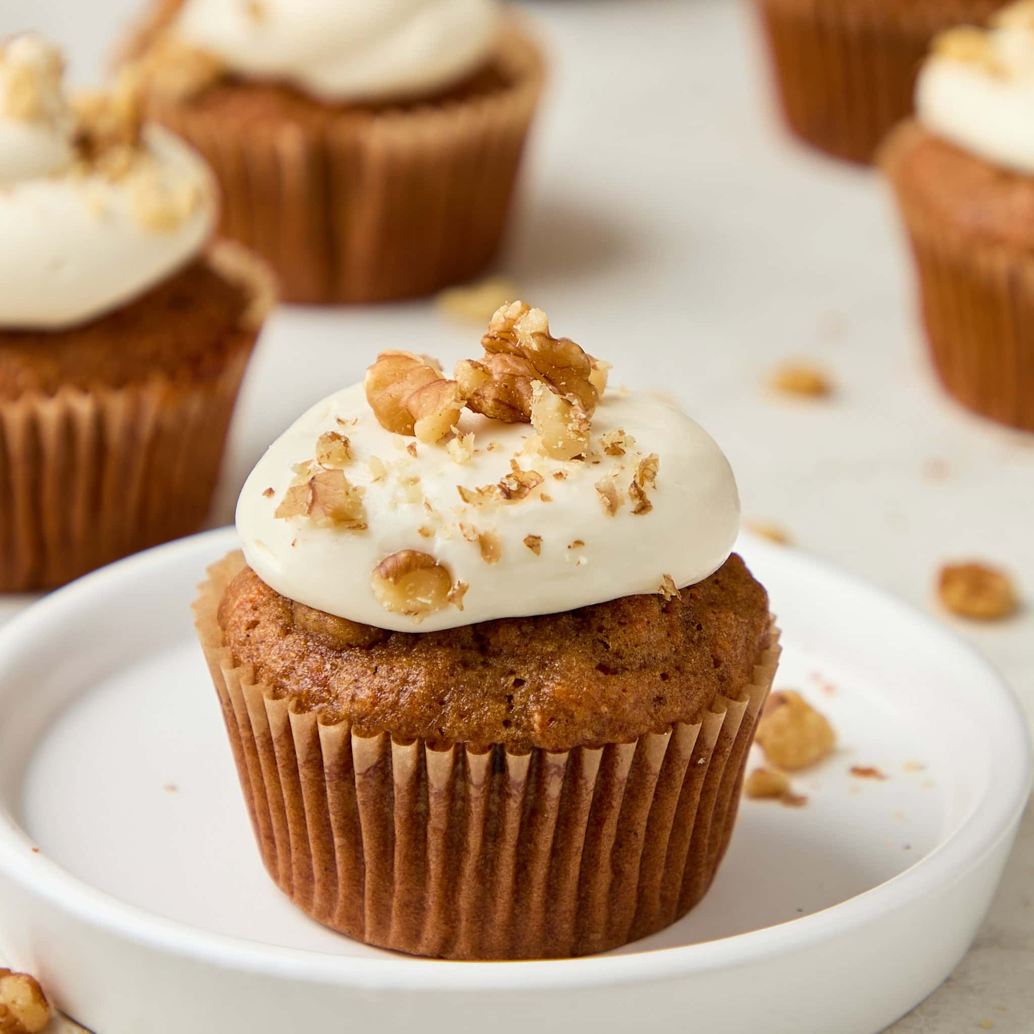 carrot cake muffin with cream cheese frosting topped with walnuts.