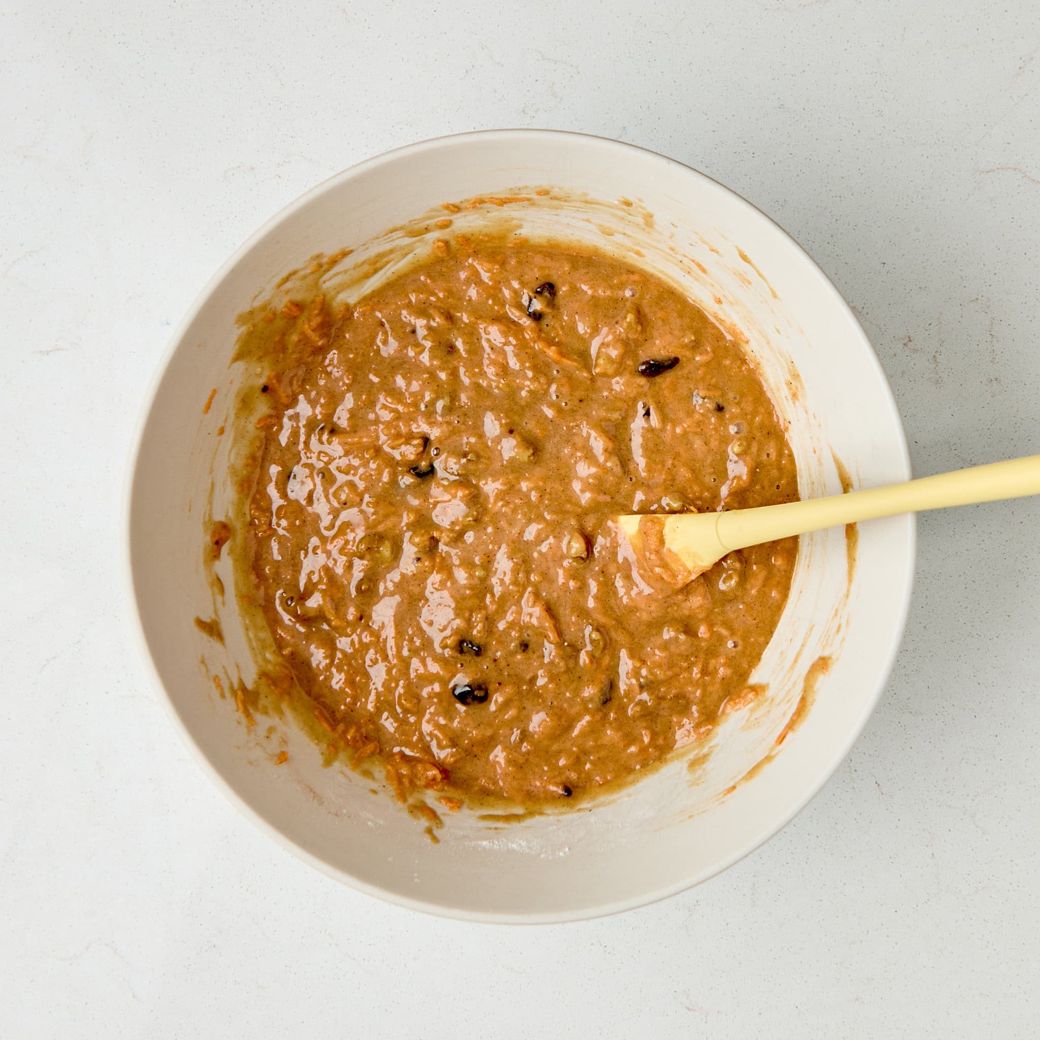 carrot cake mix in a bowl with a yellow spoon.