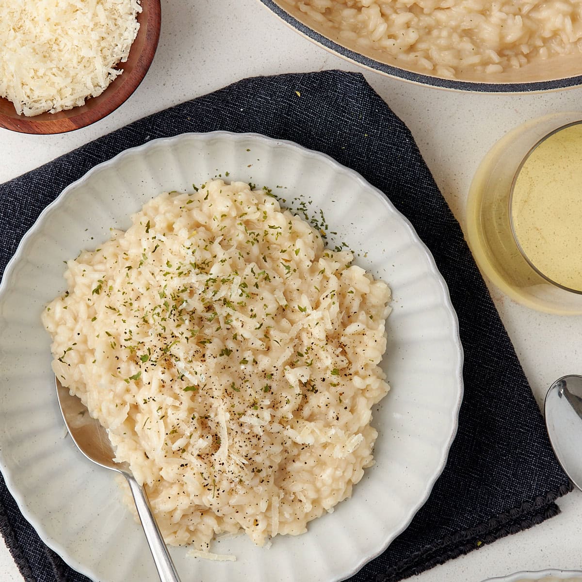 risotto in a bowl with a spoon topped with dried parsley and shredded parmesan.