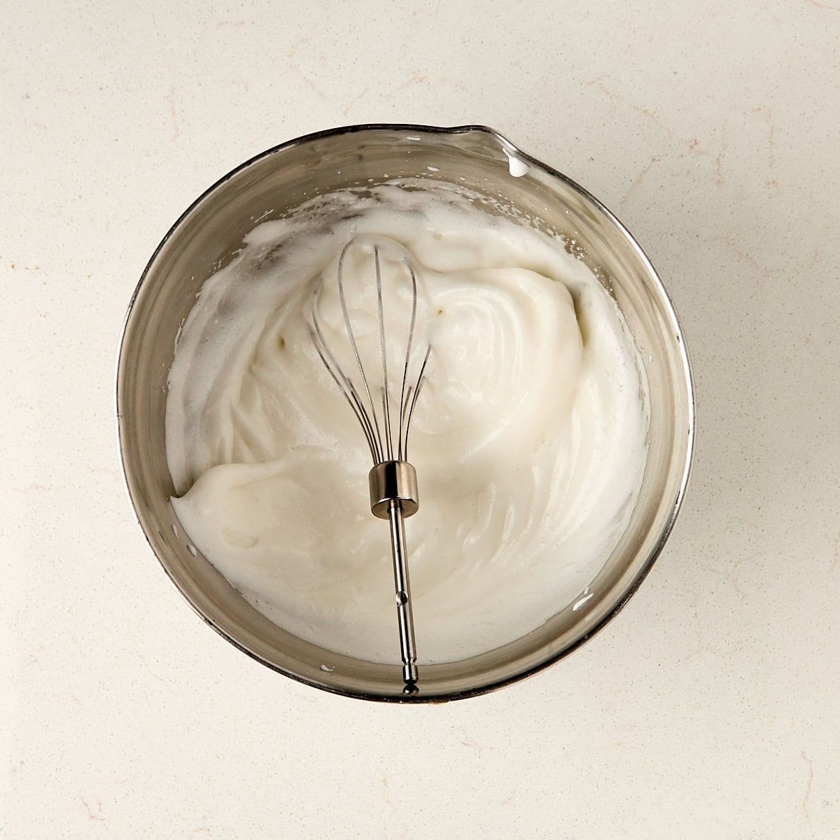 egg whites whipped in a metal bowl.