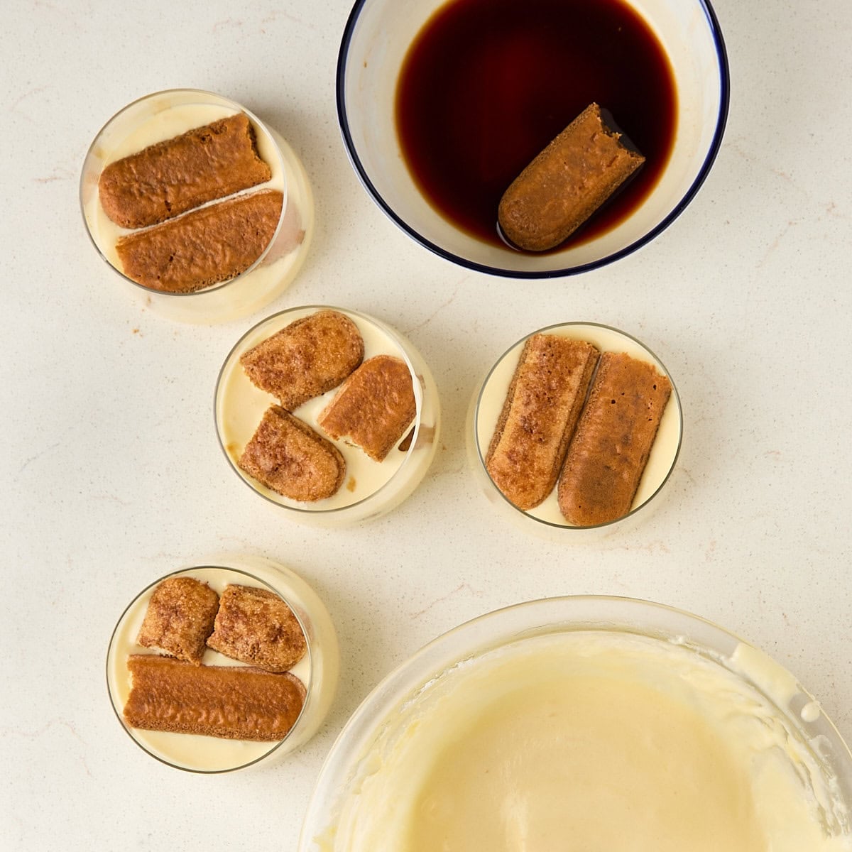 tiramisu cups that have ladyfingers soaked in espresso in cups on top of mascarpone cream.