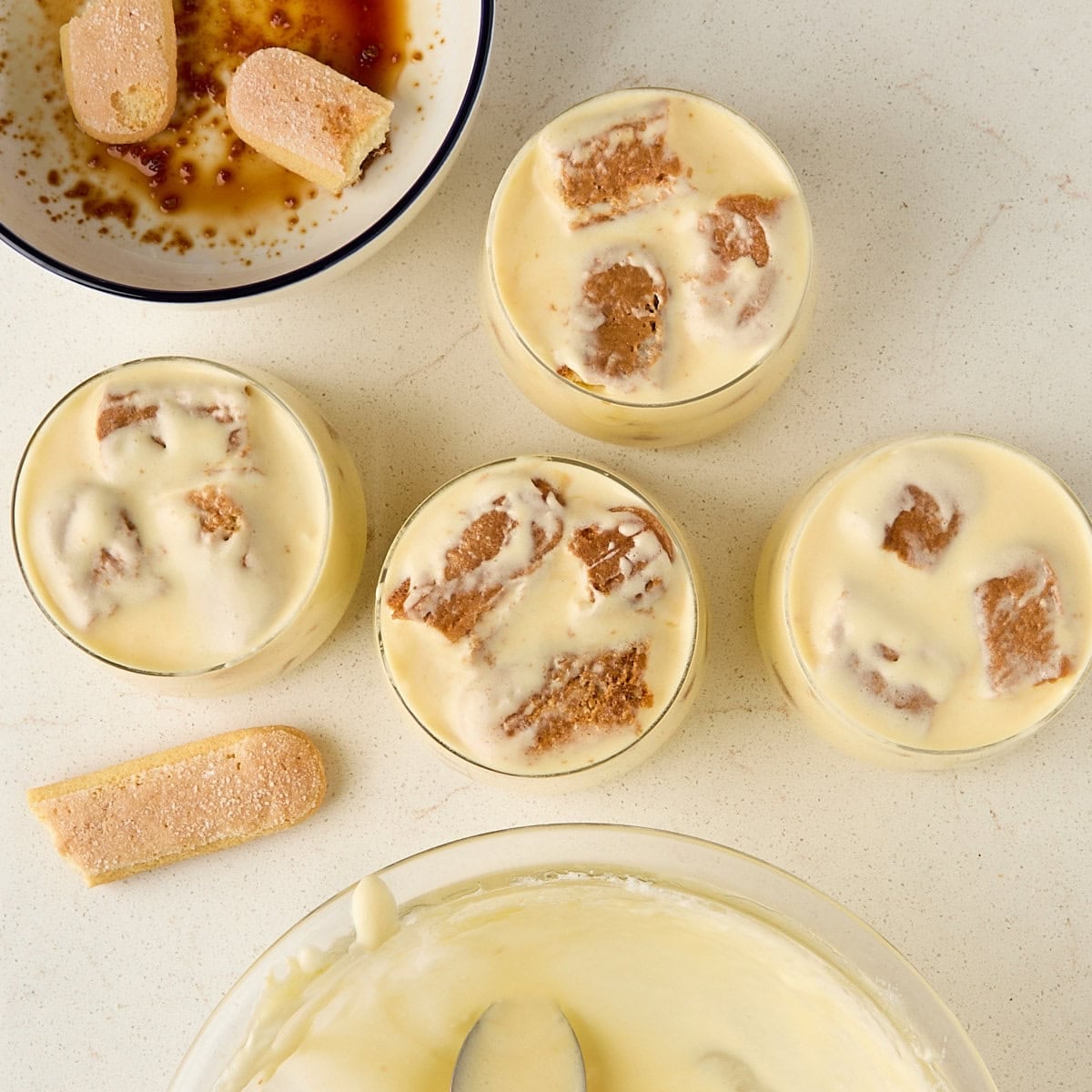 tiramisu cups that have layered with cream and ladyfingers.