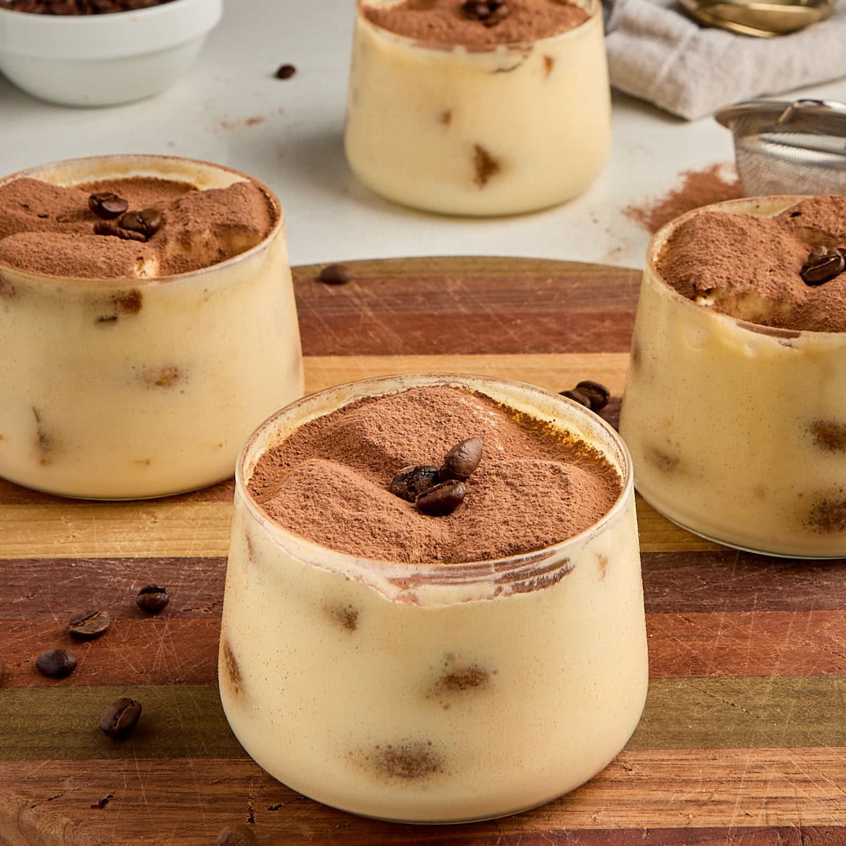 3 tiramisu cups on a wooden board.